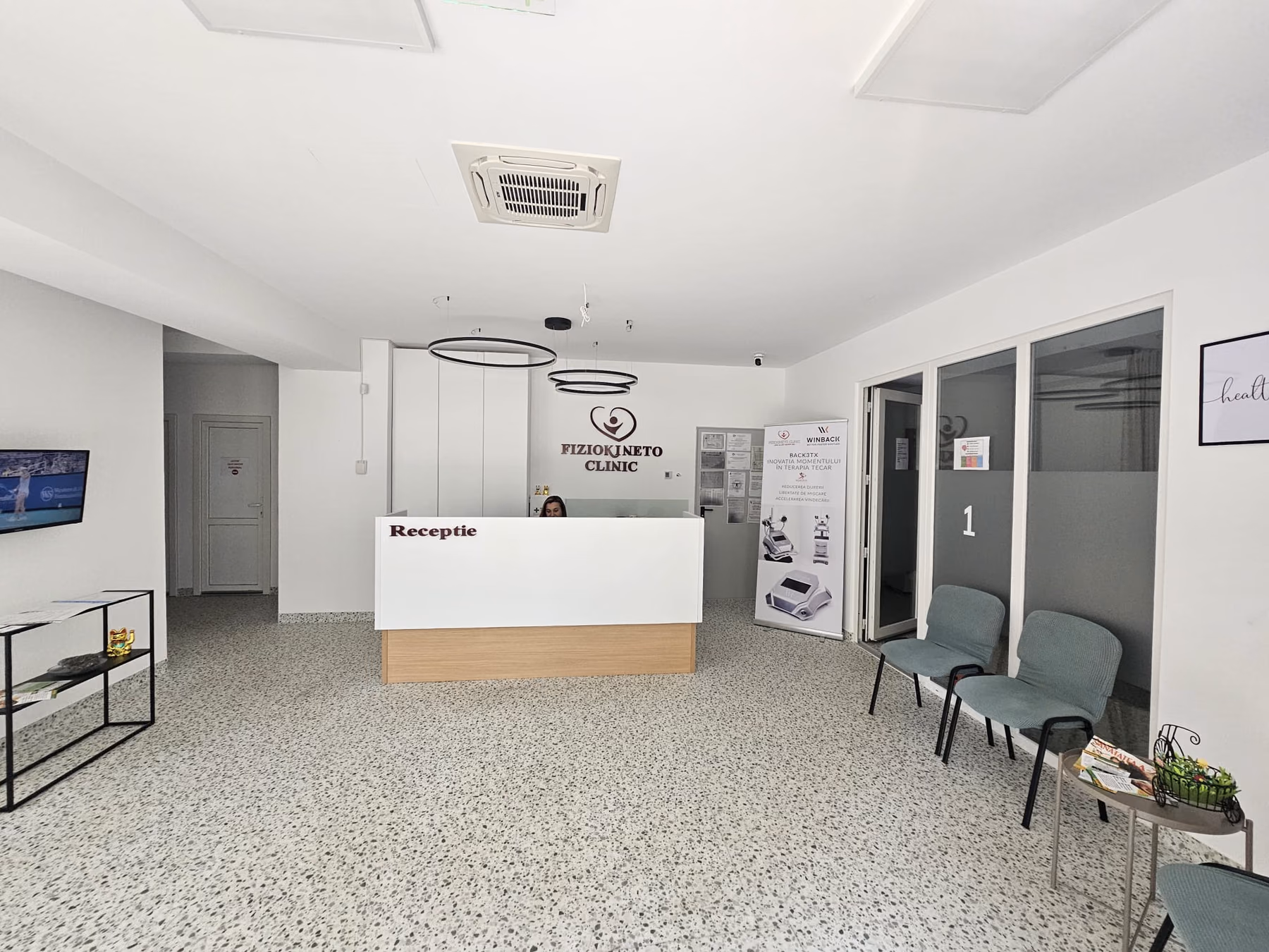 Recepția clinicii Fiziokineto, cu sigla pe perete și scaunele din zona de așteptare