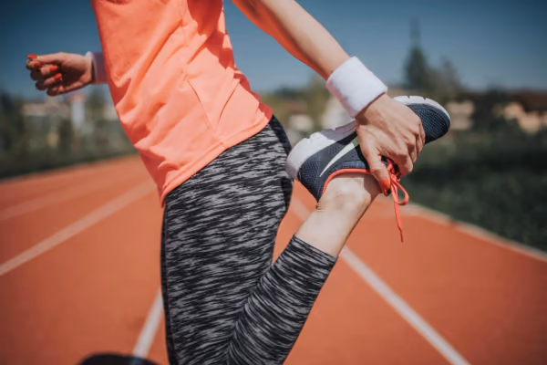 Întindere a mușchiului cvadriceps pe o pistă de atletism, încadrare de la talie în jos