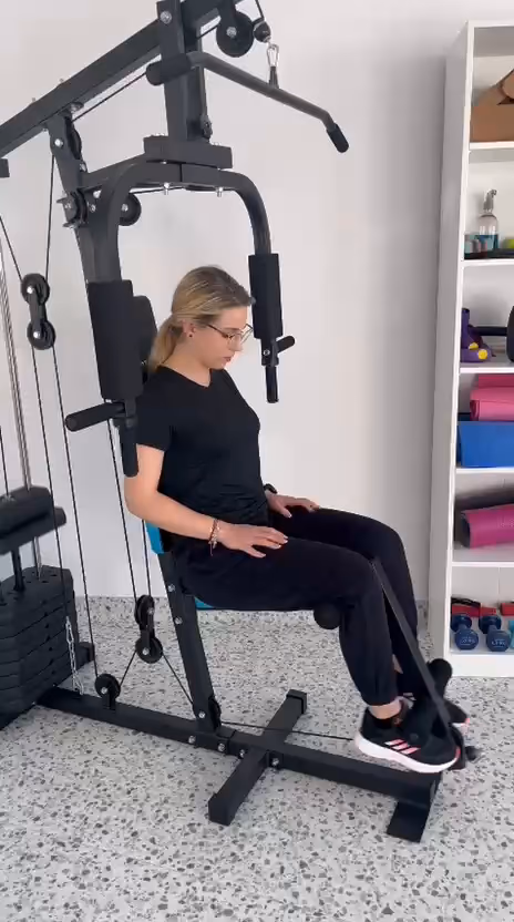 Sala de kinetoterapie a clinicii Fiziokineto, cu aparat multifuncțional și rafturi cu greutăți.